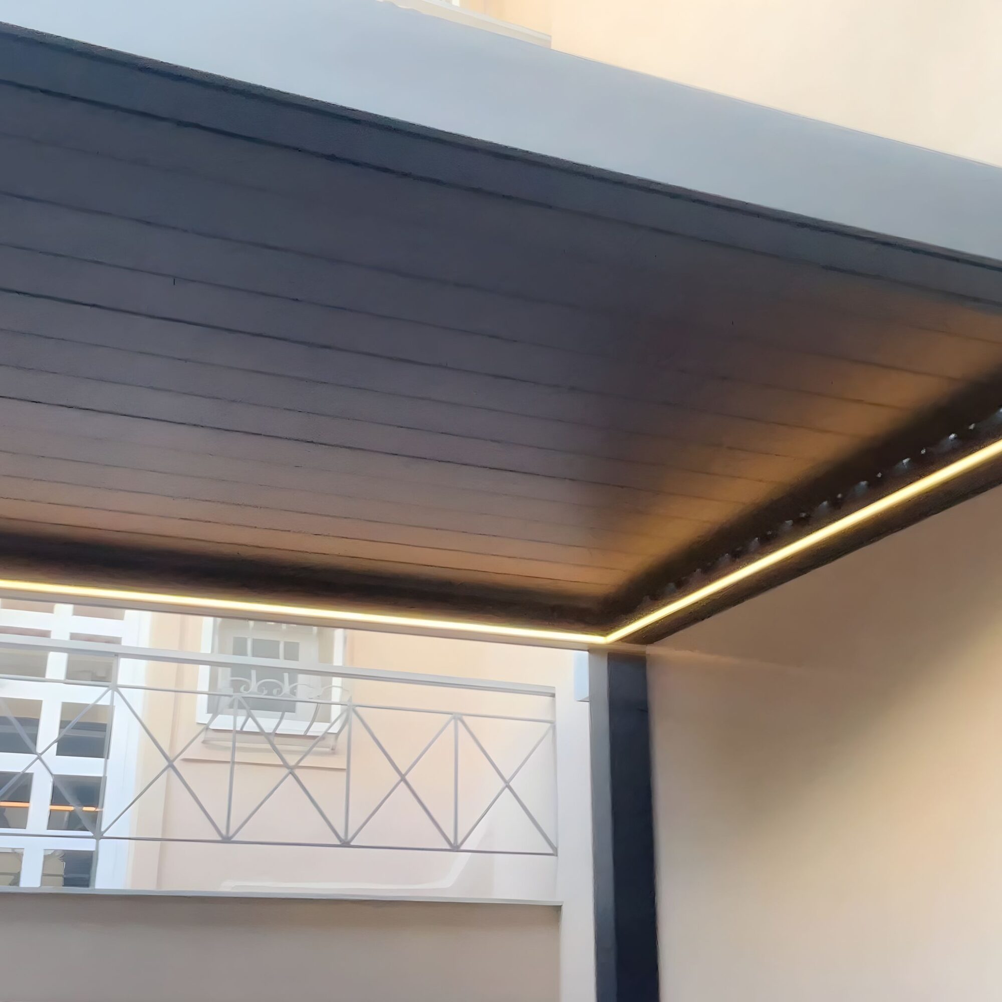 Βιοκλιματική πέργκολα με σκούρες περσίδες οροφής και περιμετρικό LED φωτισμό σε εξωτερικό χώρο κατοικίας