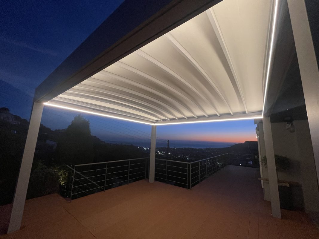 Νυχτερινή λήψη flat τεντοπέργκολας με περιμετρικό LED φωτισμό σε υπερυψωμένη βεράντα με θέα στο Λαγονήσι.