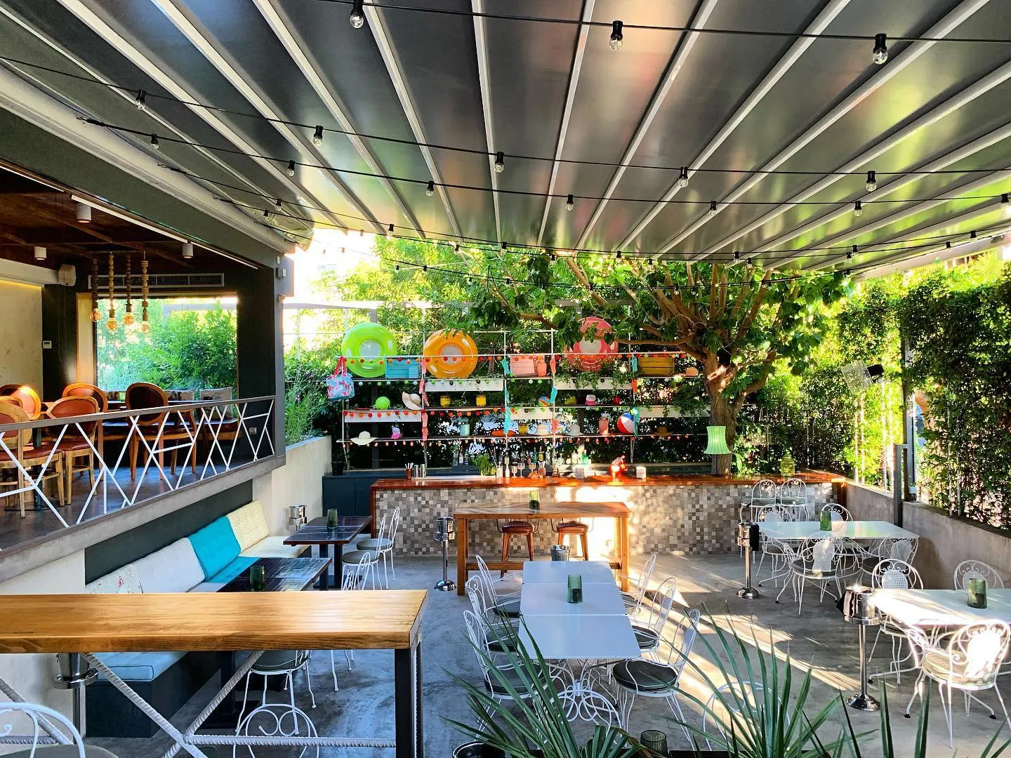 Πέργκολα αλουμινίου με ενσωματωμένο φωτισμό σε εξωτερικό χώρο καφετέριας, προσφέροντας σκίαση και κομψότητα.