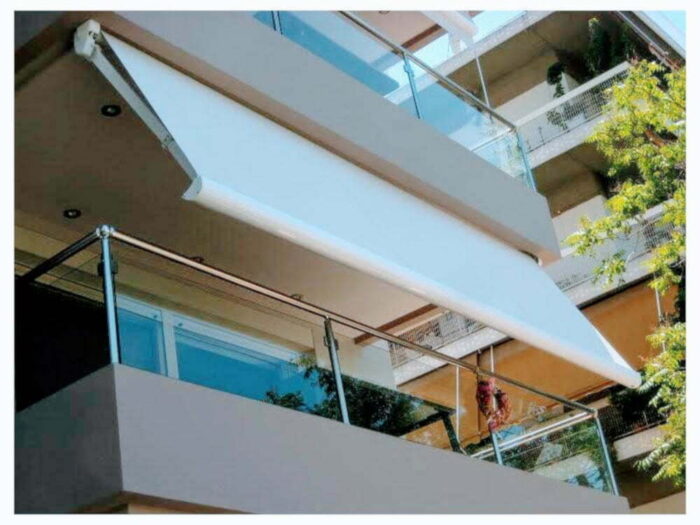 Κομψή λευκή τέντα σε μπαλκόνι διαμερίσματος, προσφέροντας λειτουργικότητα και αισθητική.