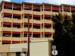 Εξωτερική όψη κτηρίου με εντυπωσιακές κόκκινες τέντες, που προσφέρουν σκίαση και αισθητική αρμονία.