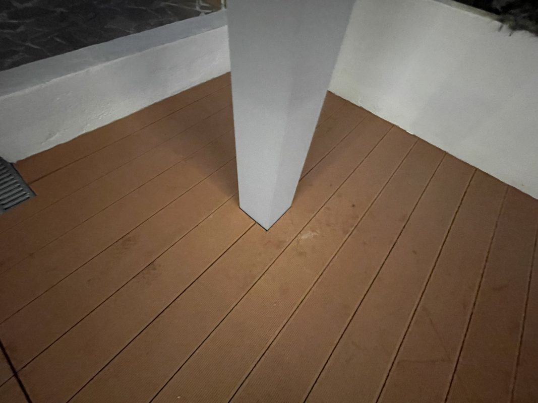 Λεπτομέρεια της βάσης στήριξης κολώνας flat τεντοπέργκολας σε ξύλινο δάπεδο σε εξωτερικό χώρο.