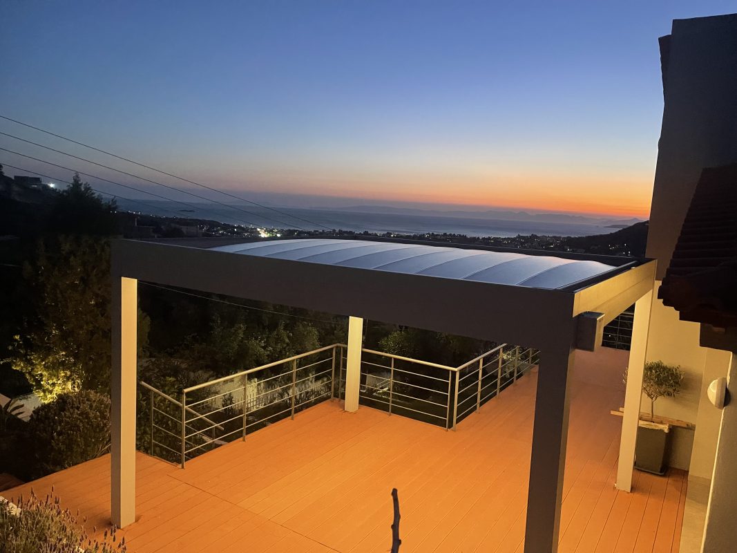 Πανοραμική λήψη flat τεντοπέργκολας σε βεράντα με θέα στο ηλιοβασίλεμα και τον κόλπο του Λαγονησίου.