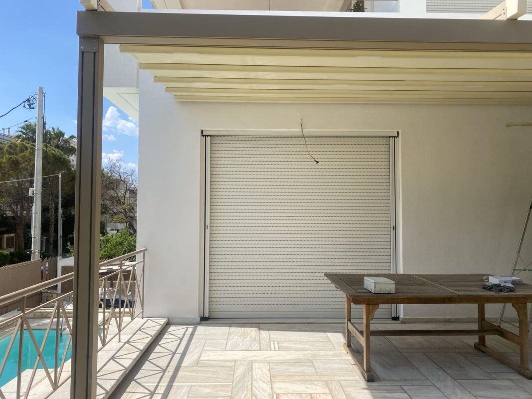 Λεπτομέρεια εγκατάστασης τεντοπέργκολας αλουμινίου σε μπαλκόνι με ξύλινο τραπέζι